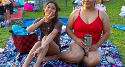 Two women sitting on a blanket.