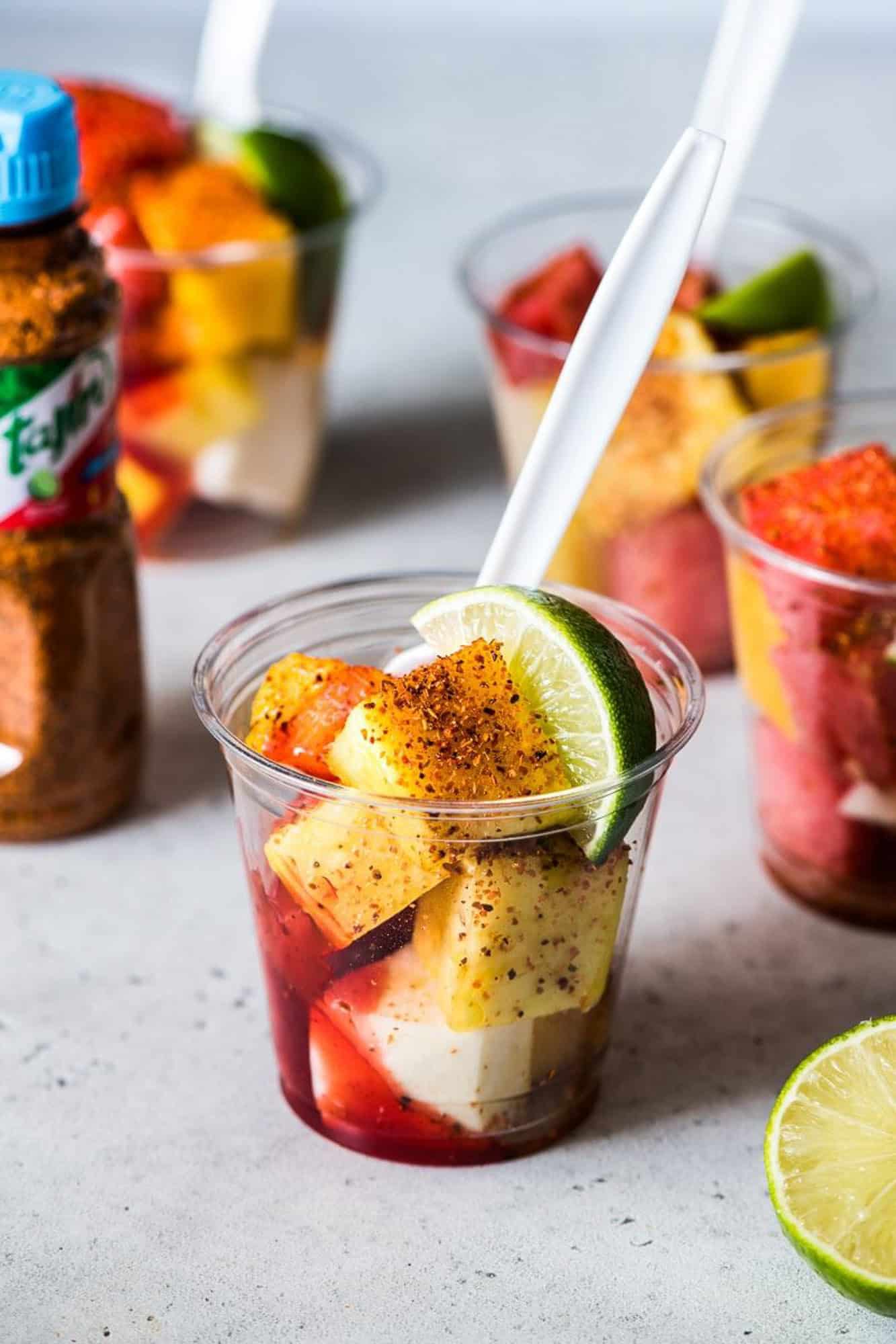 A bowl of fruit and a bottle of ketchup on a table.