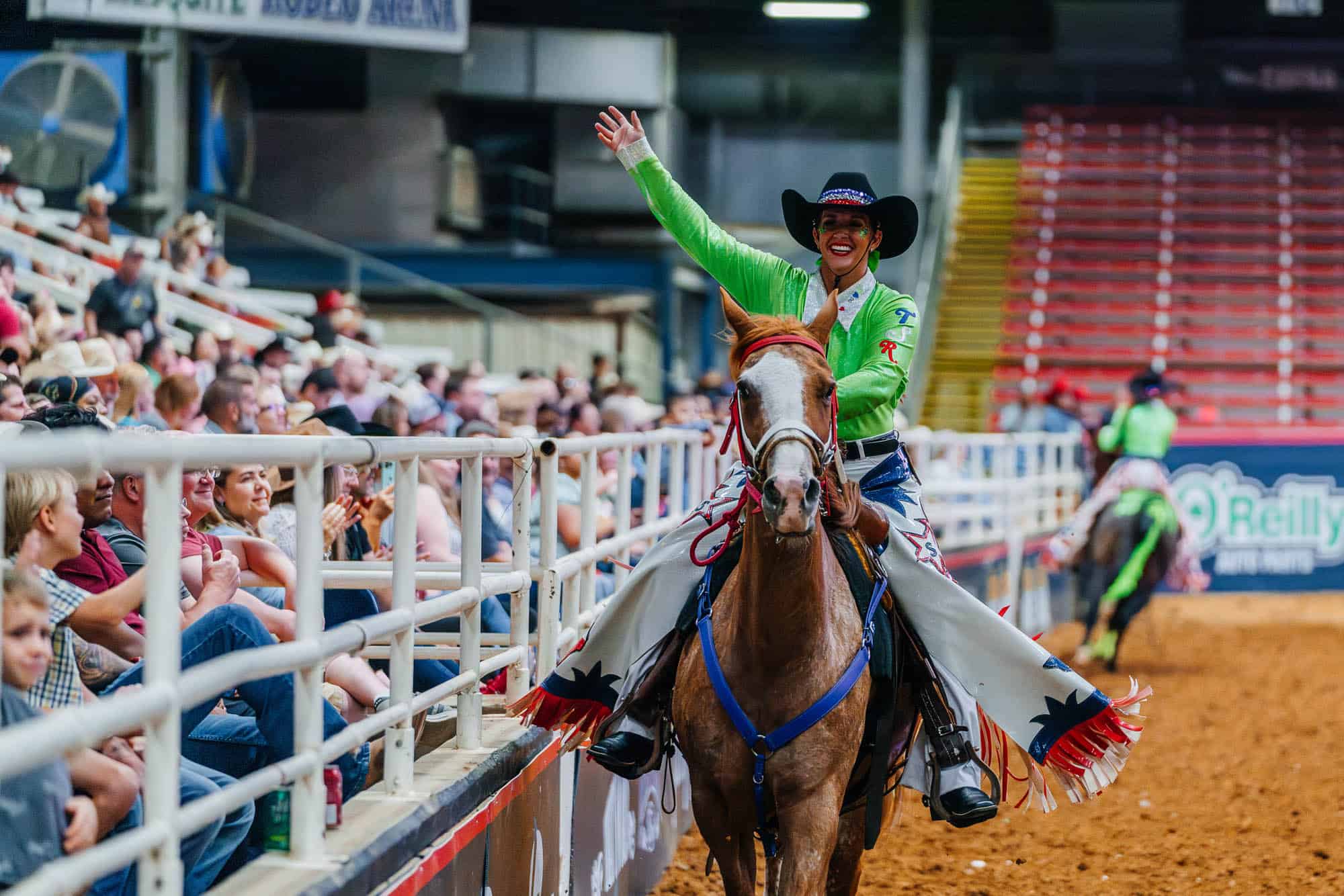 A woman riding a horse in a rodeo arena.