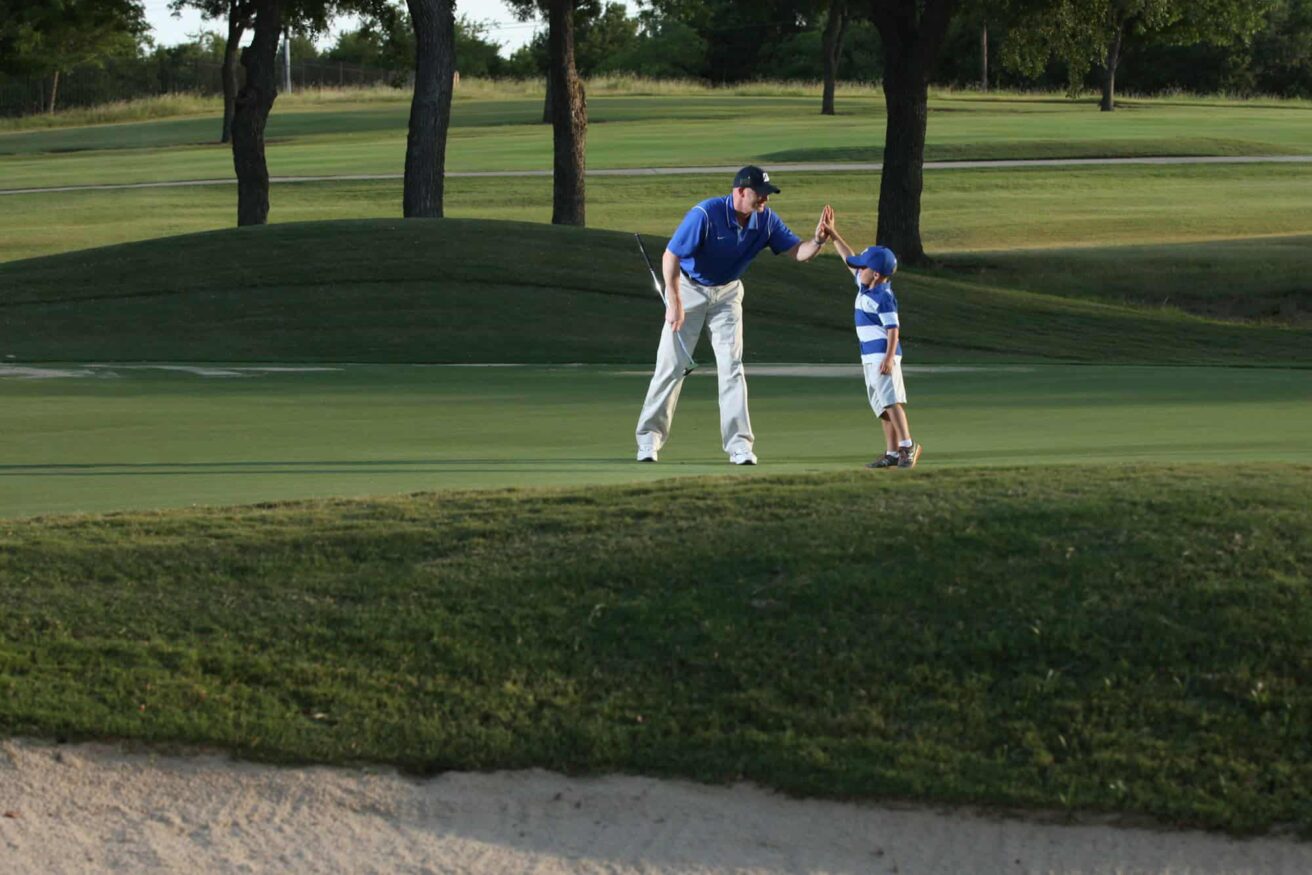 A man and a child on a golf course.