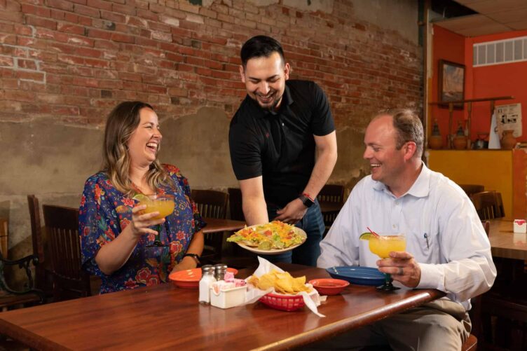 A man and a woman sitting at a table with a plate of food.