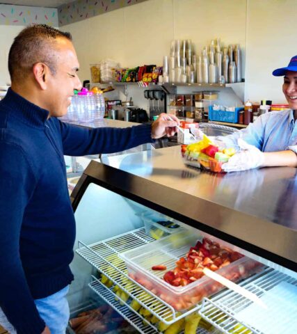 A group of people standing in front of a counter at a ice cream shop.