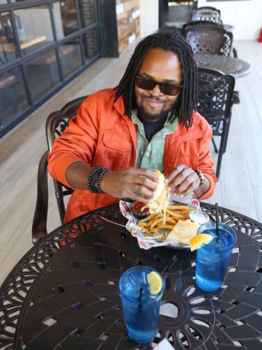 A man sitting at a table eating a sandwich.