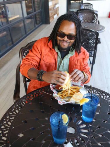 A man sitting at a table eating a sandwich.