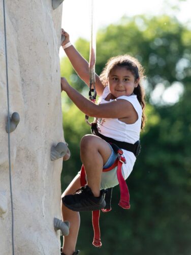 A girl climbing a rock wall.