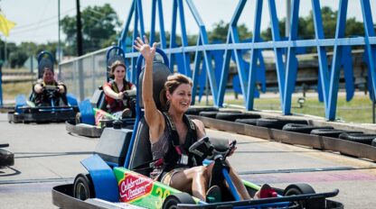 A woman is riding a go - kart at an amusement park.