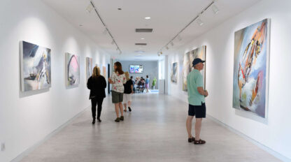 A group of people looking at paintings in an art gallery.