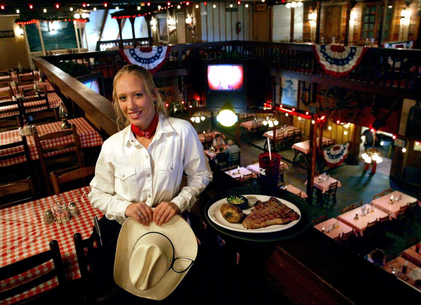 A woman in a cowboy hat holding a plate of food.