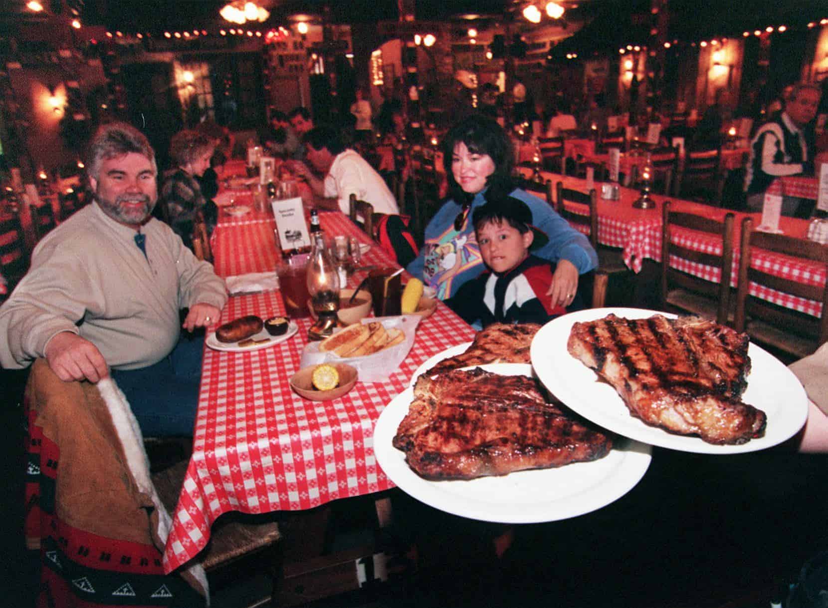 A man holding a plate of steak.