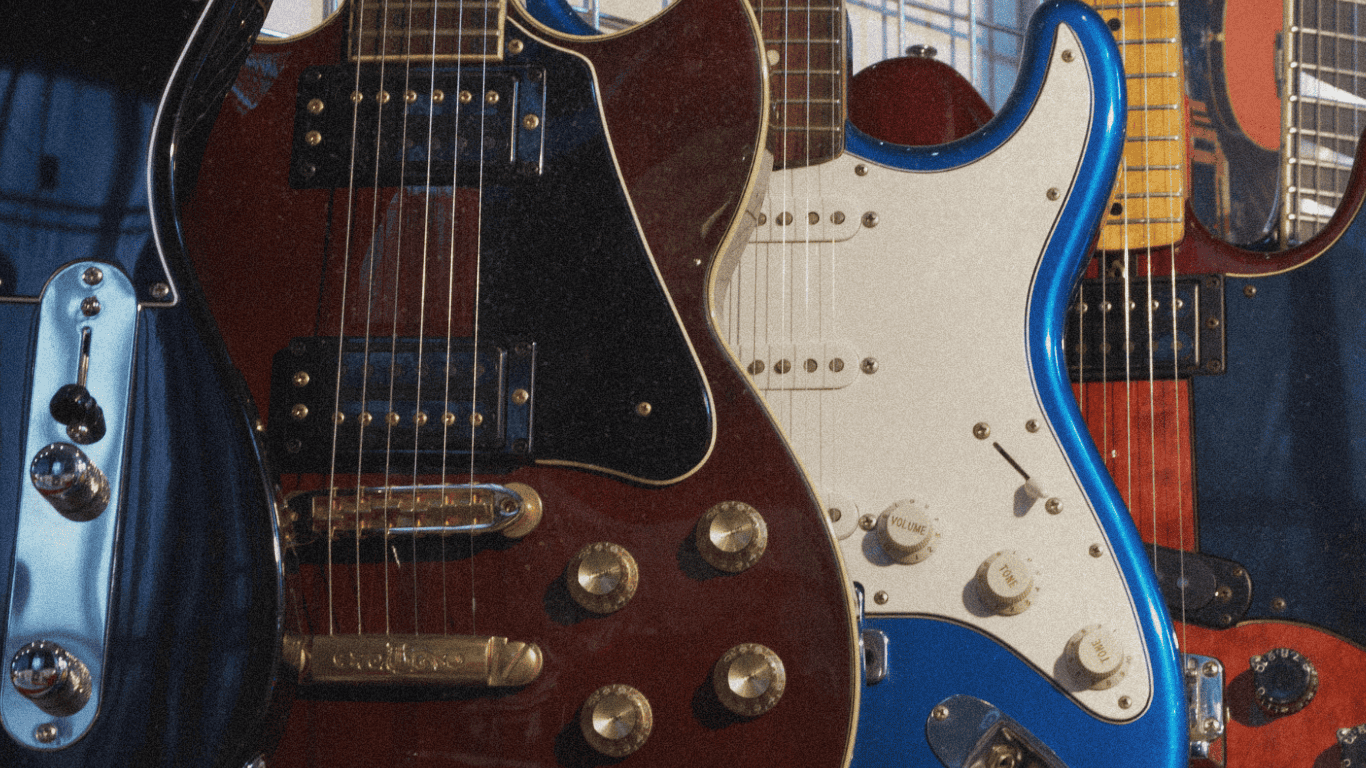 Close-up of a row of electric guitars with various designs and colors, including a brown guitar with gold knobs and a blue and white guitar.