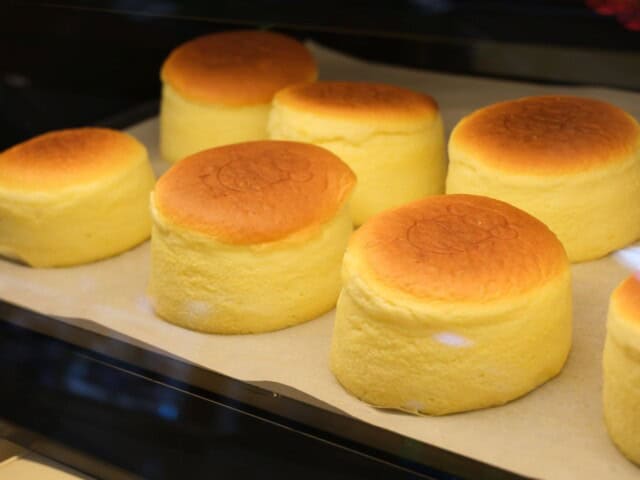 Several fluffy, golden-brown Japanese soufflé cheesecakes are displayed on a baking tray lined with parchment paper.
